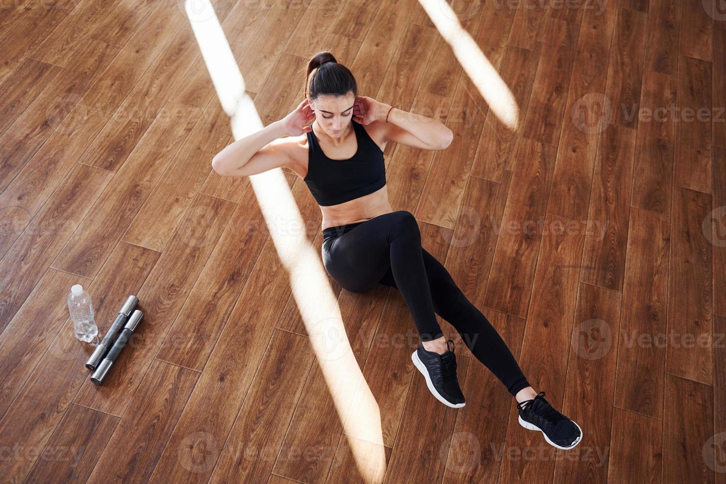 On the floor illuminated by light beams. Young sporty woman in sportswear doing fitness in the gym photo
