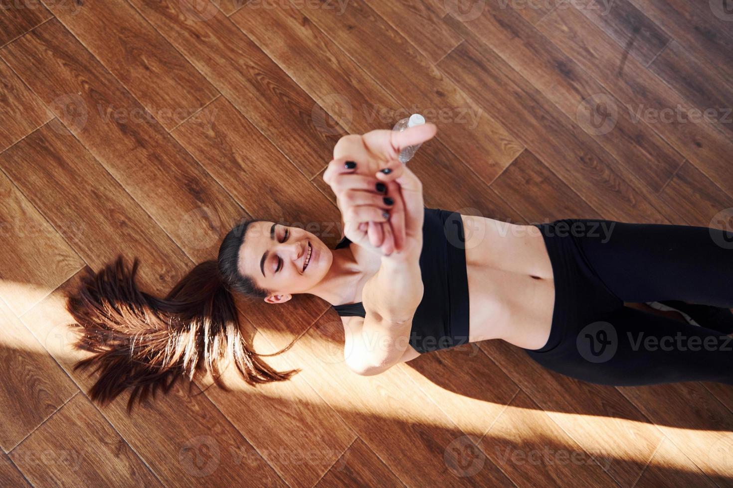 On the floor illuminated by light beams. Young sporty woman in sportswear resting photo