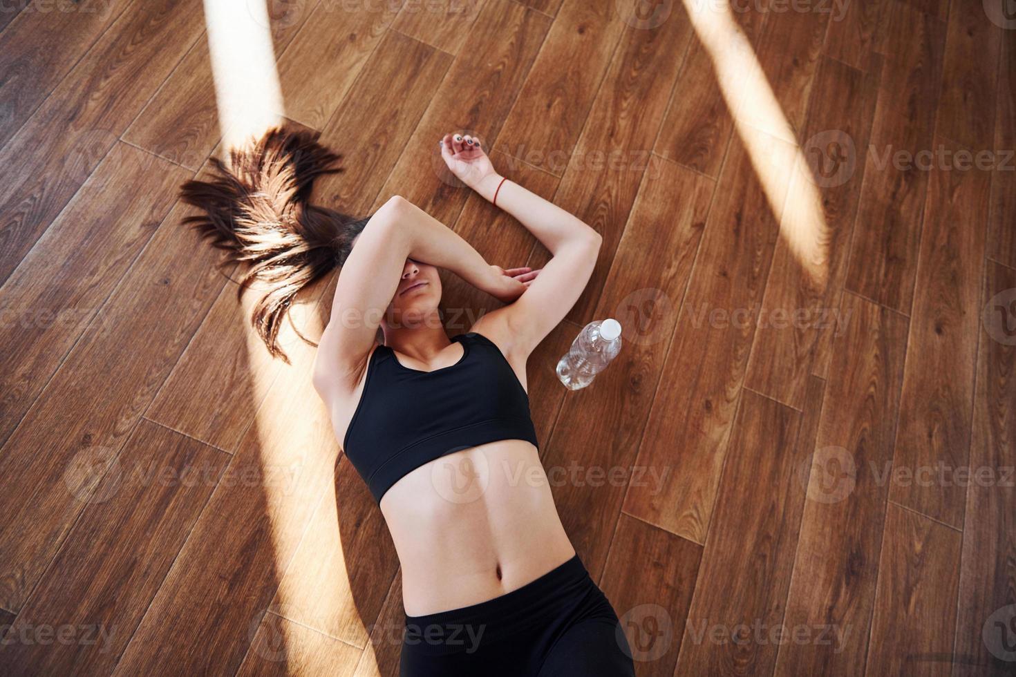 On the floor illuminated by light beams. Young sporty woman in sportswear resting photo