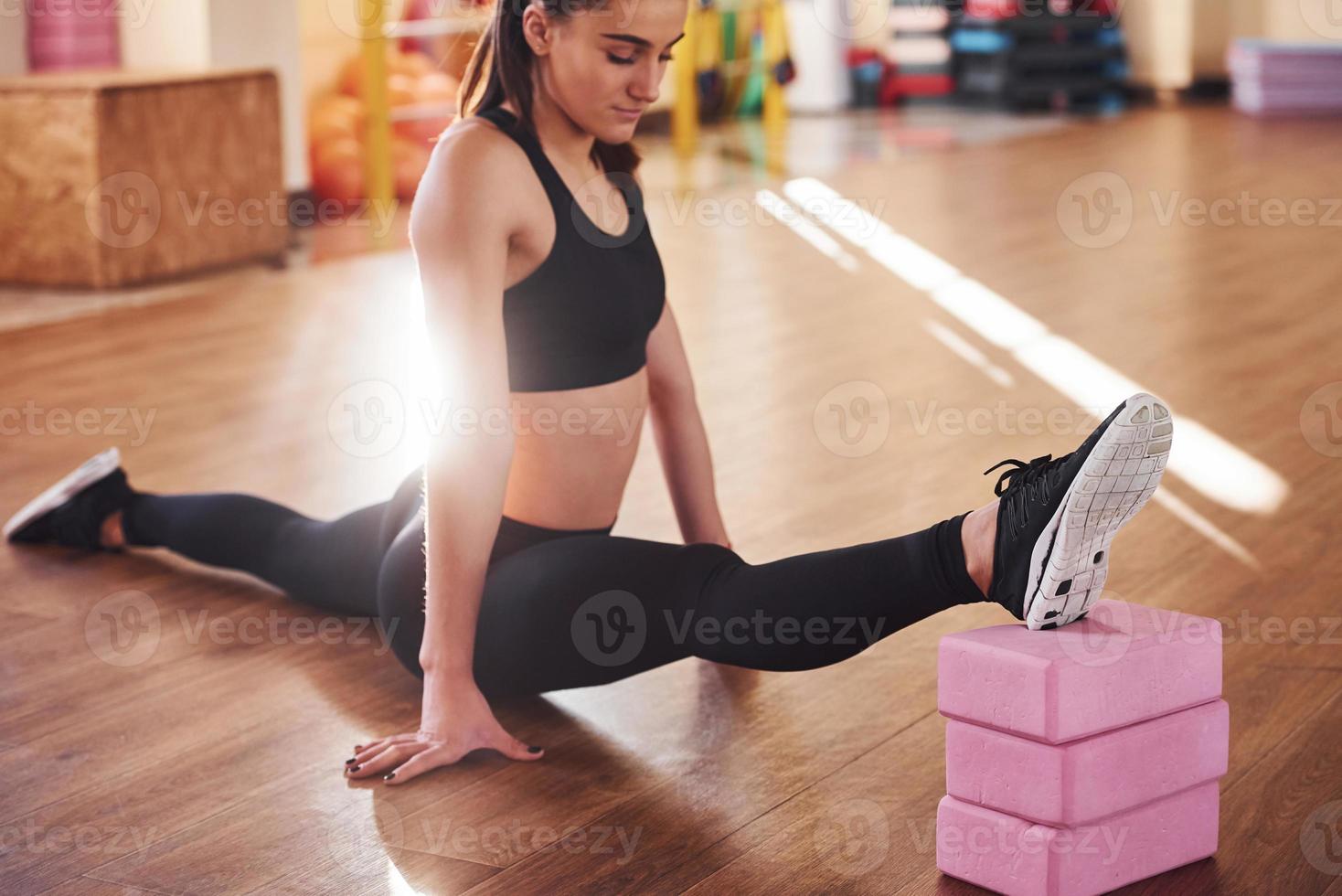 Beautiful sporty woman in sportswear doing stretching by using equipment on the floor photo