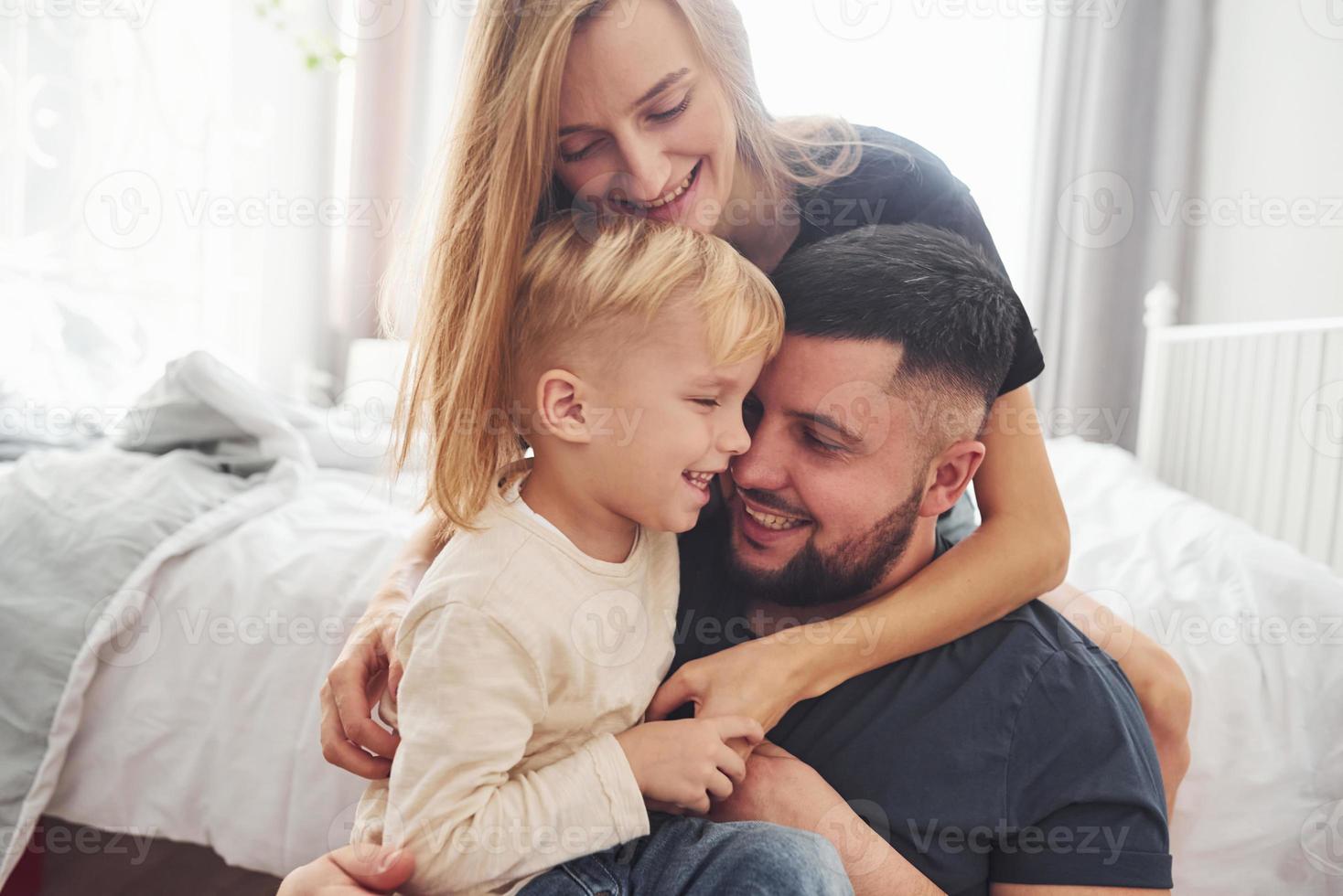 una pareja casada joven con su hijo pequeño tiene tiempo libre juntos en el dormitorio durante el día foto