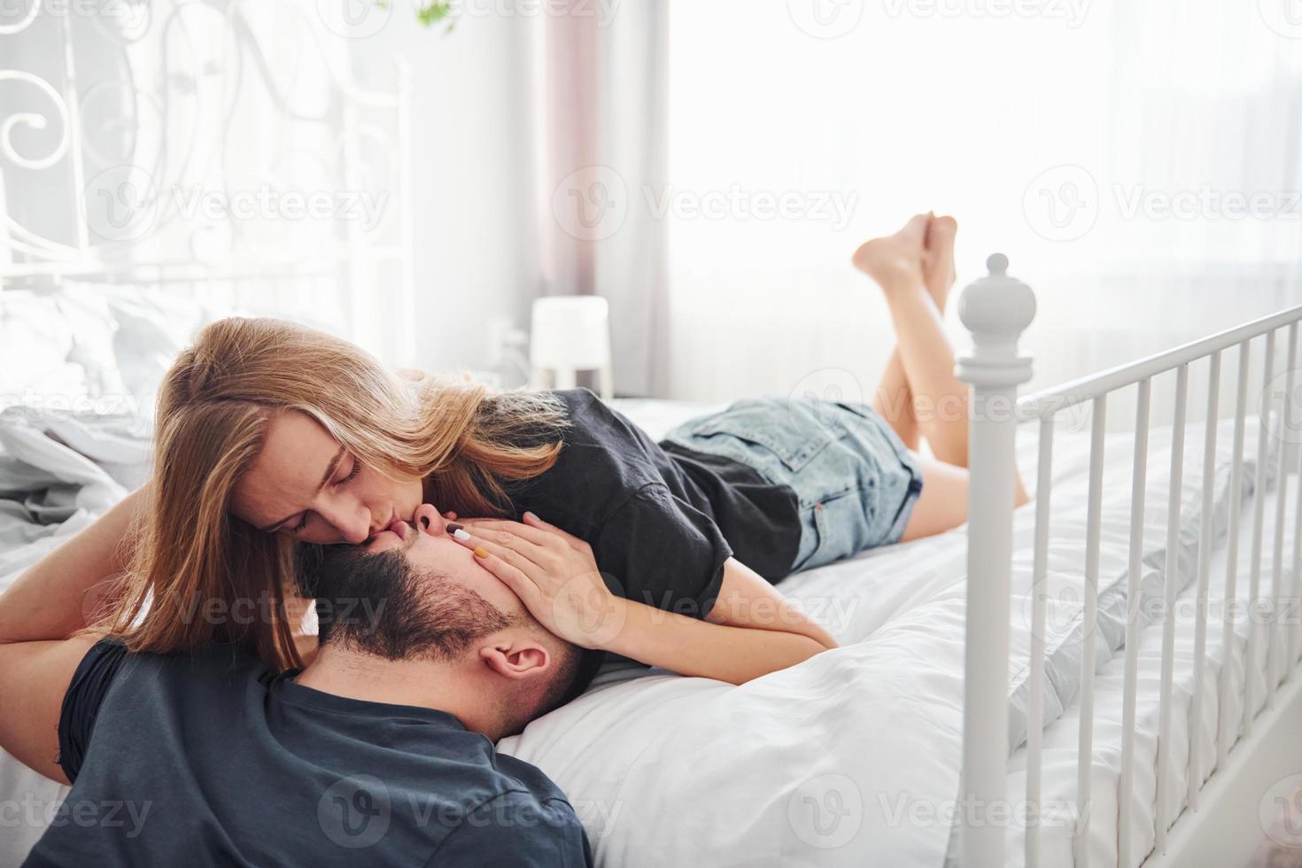 Young married couple kissing each other in bedroom at daytime photo