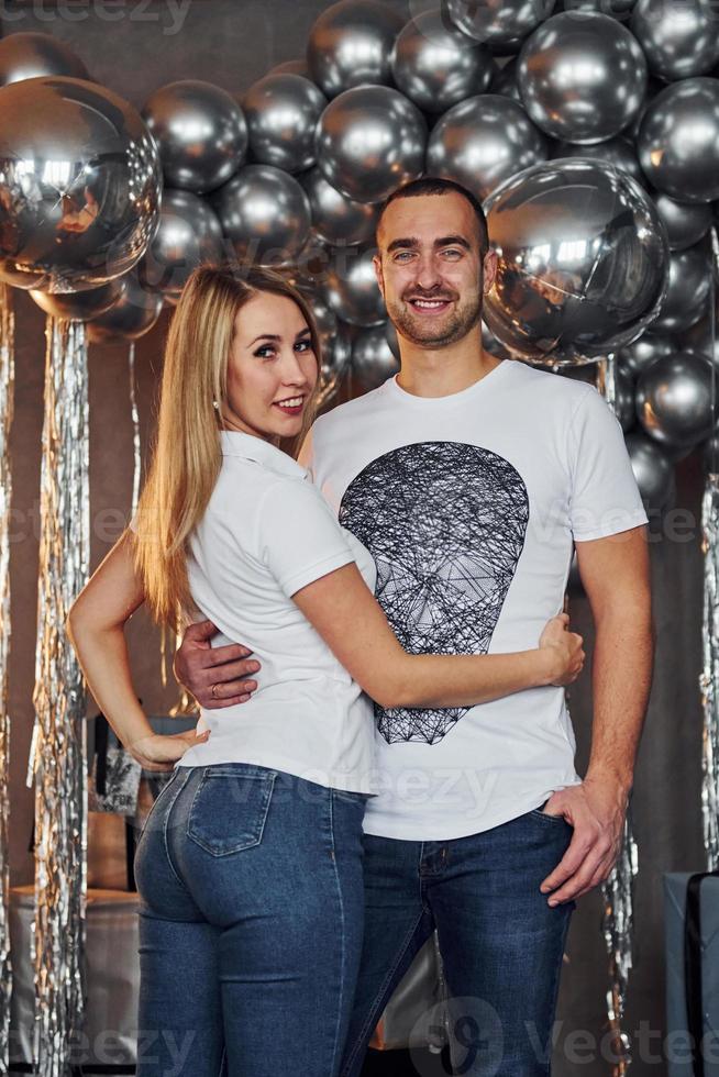 Couple is in christmas decorated room with balloons embracing each other together. Celebrating New Year photo