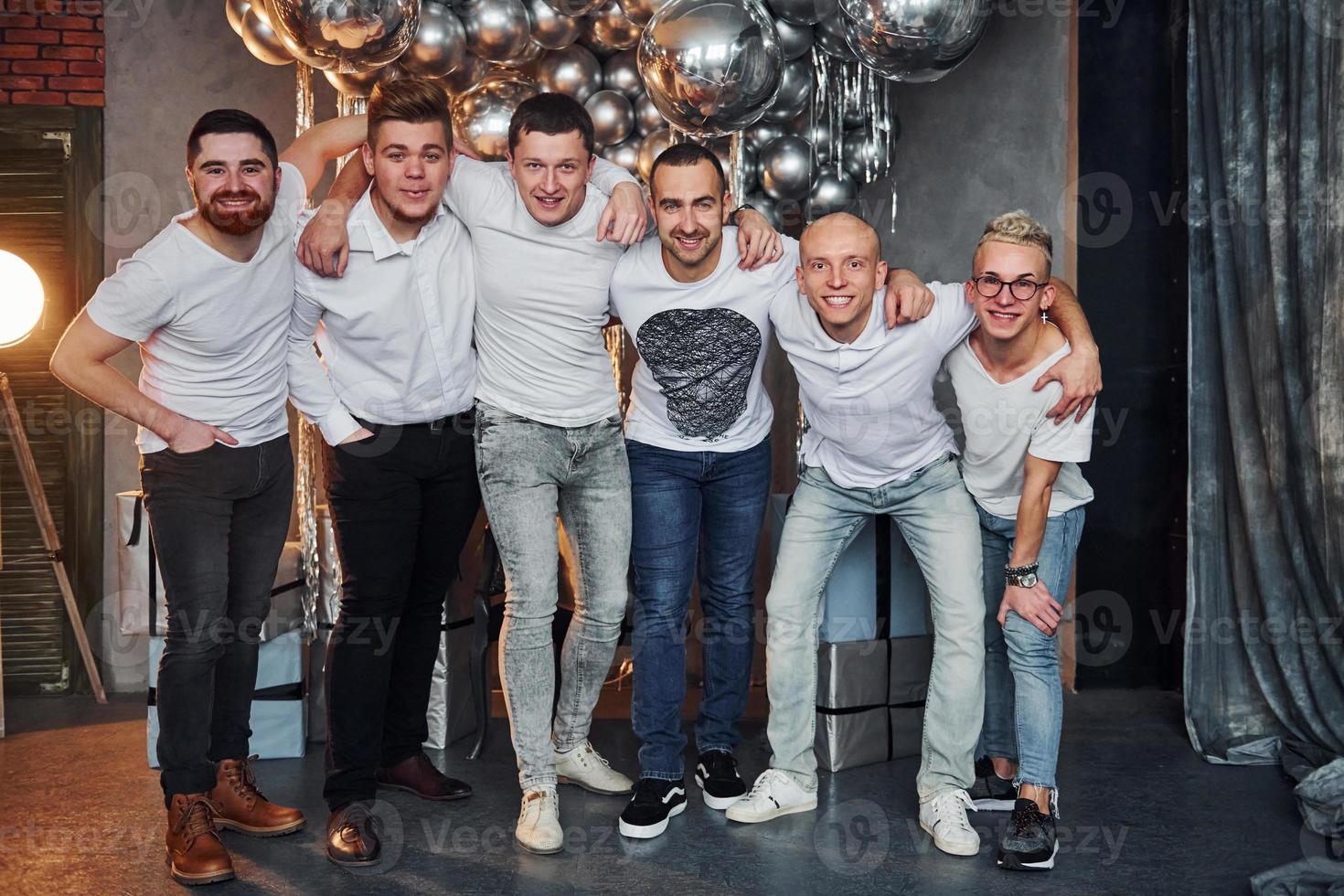Group of cheerful men standing together in christmas decorated room and posing for a camera photo