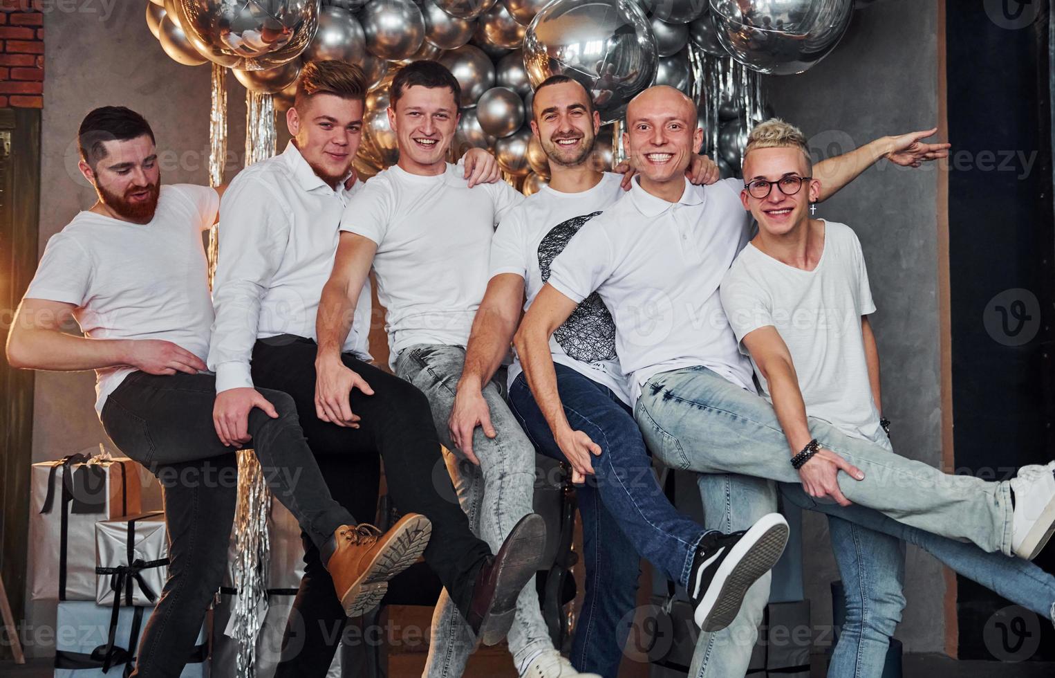 Group of cheerful men standing together in christmas decorated room and posing for a camera photo