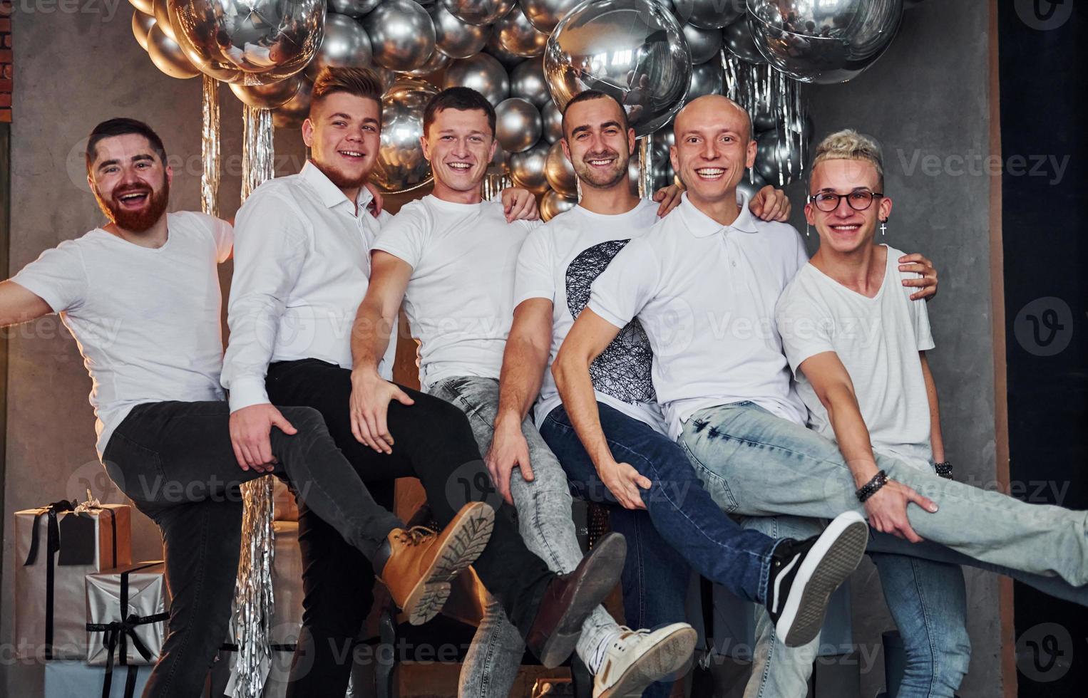 Group of cheerful men standing together in christmas decorated room and posing for a camera photo