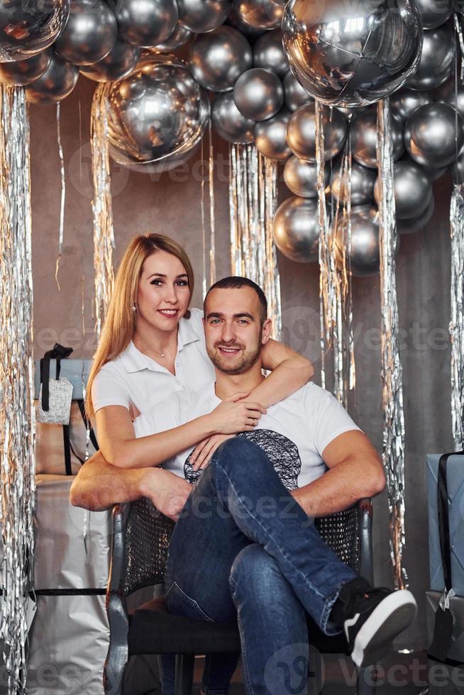Couple is in christmas decorated room with balloons embracing each other together. Celebrating New Year photo