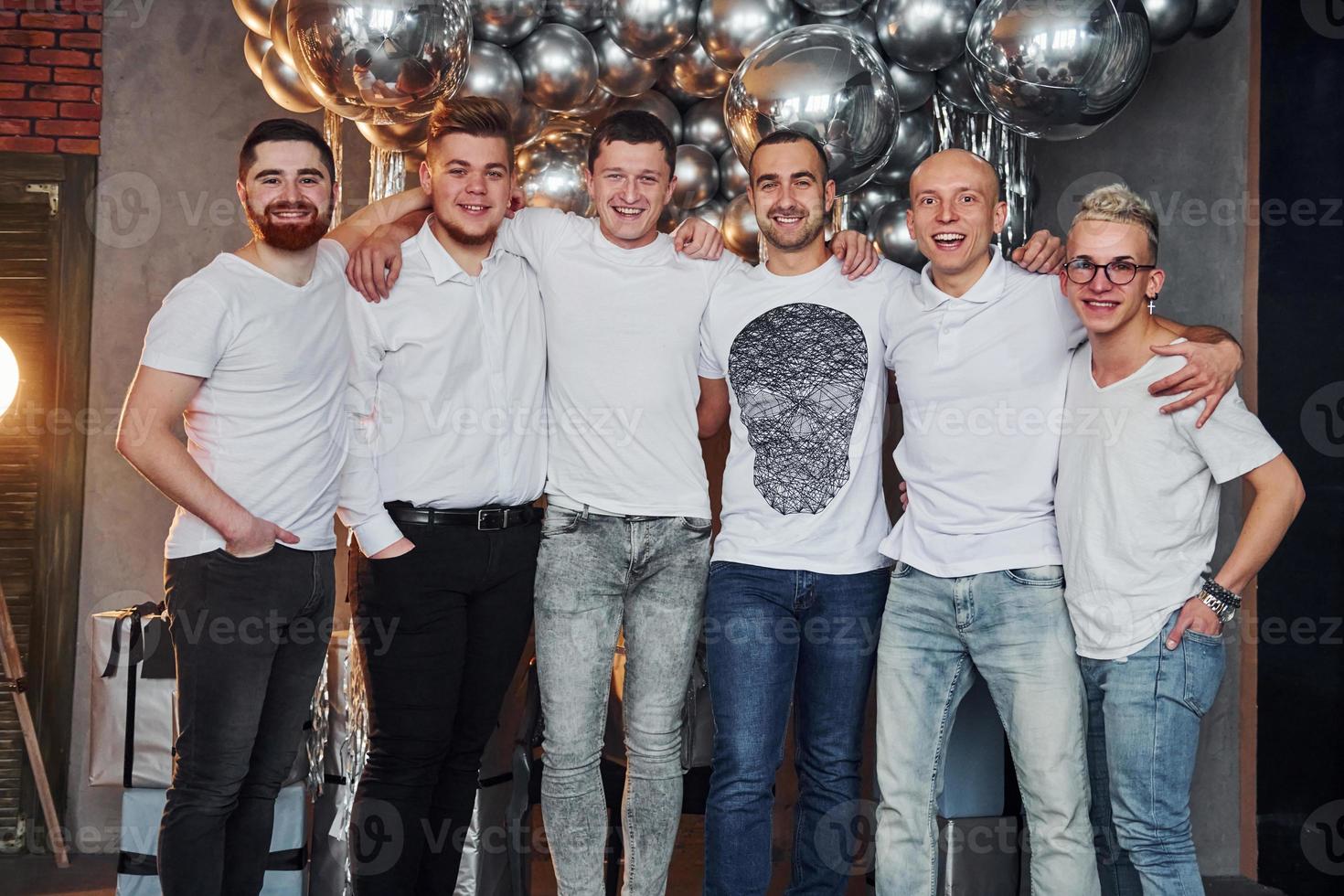 Group of cheerful men standing together in christmas decorated room and posing for a camera photo