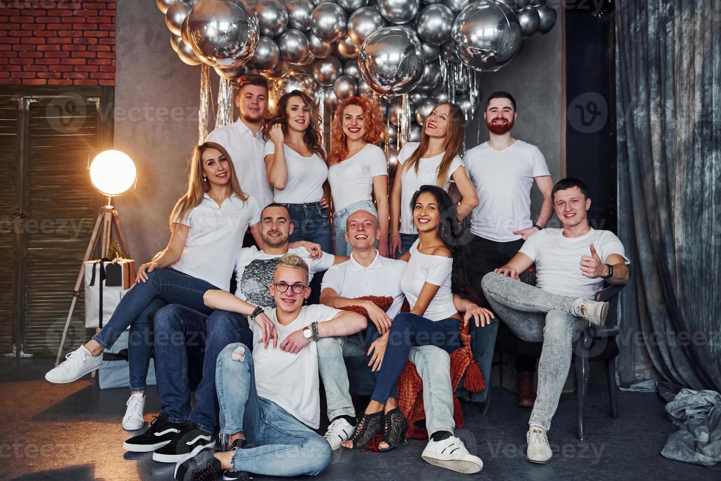 Positive young people sitting and celebrating New Year in christmas decorated room with balloons together photo