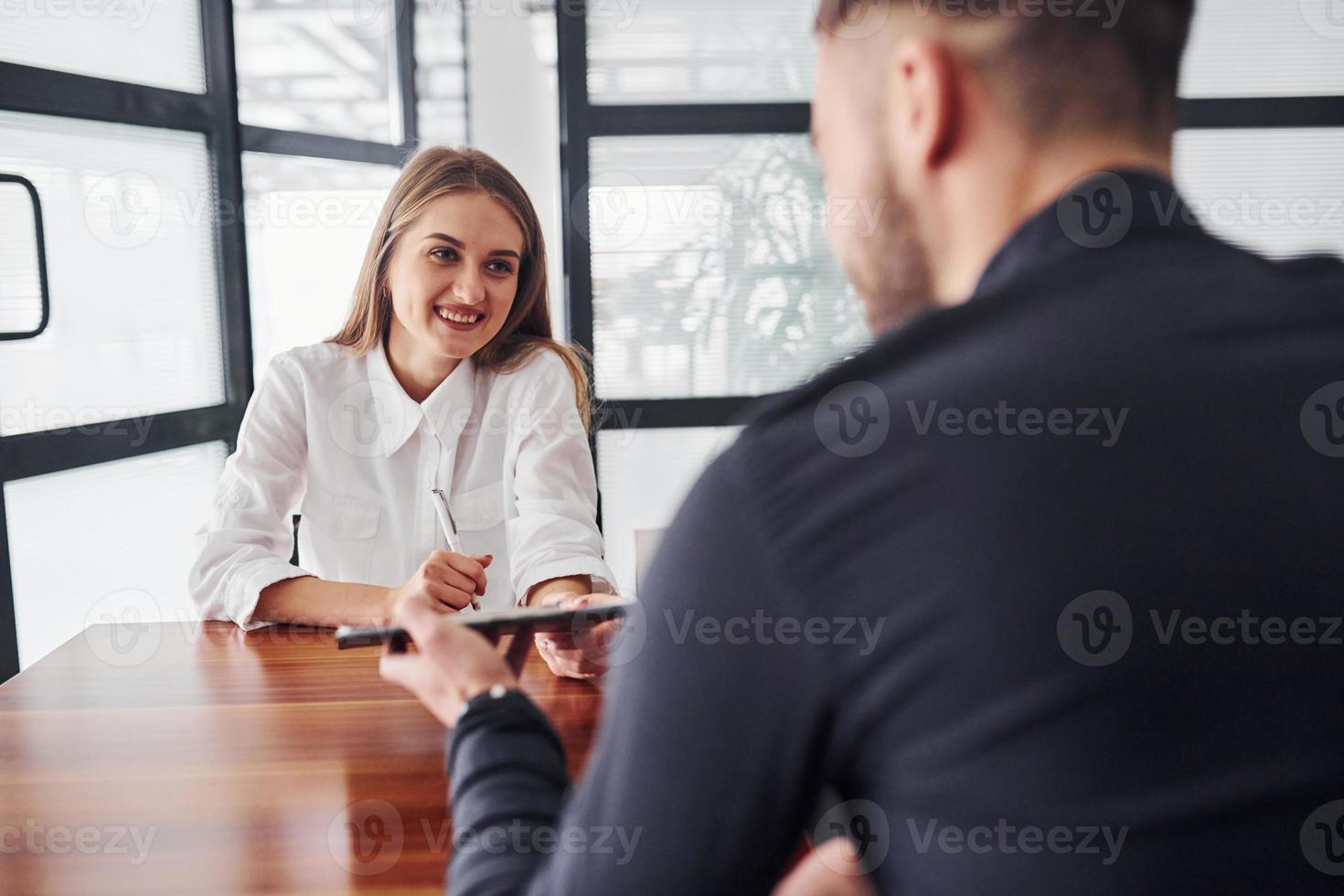 vista trasera. mujer y hombre con ropa formal trabajando juntos en el interior de la oficina junto a la mesa foto