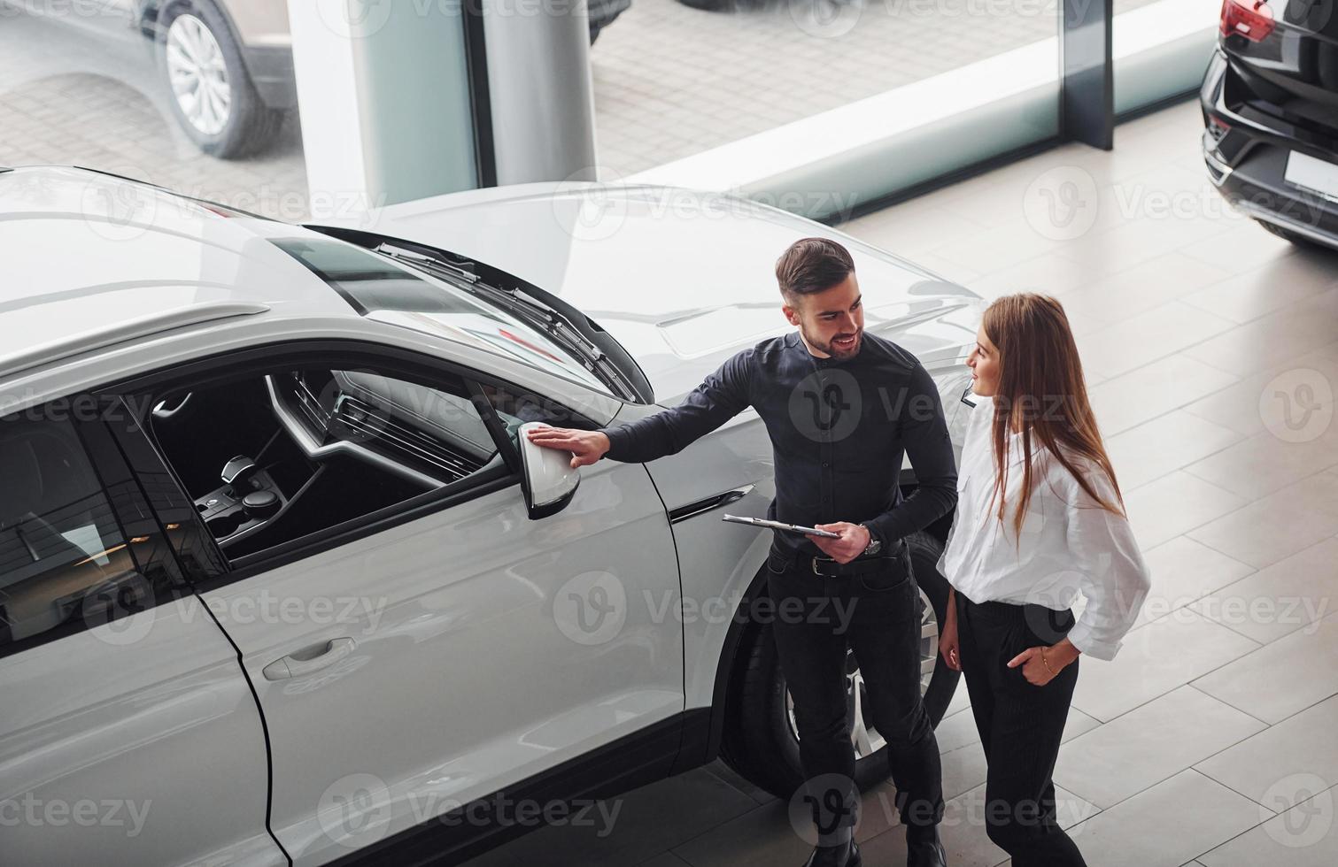 mujer eligiendo coche con la ayuda de un asistente masculino en el interior del salón foto
