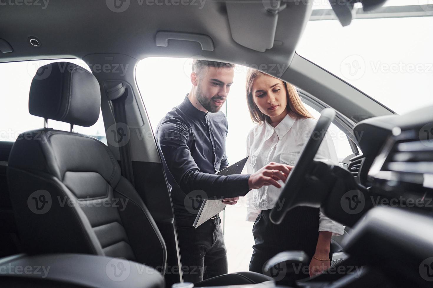 Woman choosing car by help of male assistant indoors in the salon photo