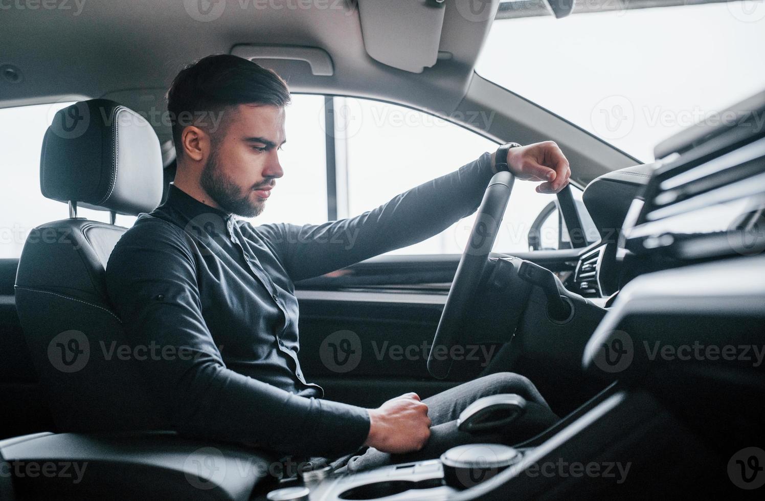 Man in elegant clothes sitting in brand new expencive automobile photo