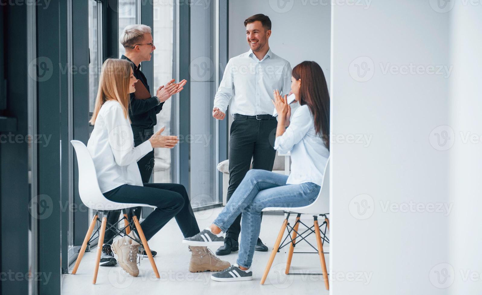 Group of young successful team have work and communicating together indoors in office near windows photo