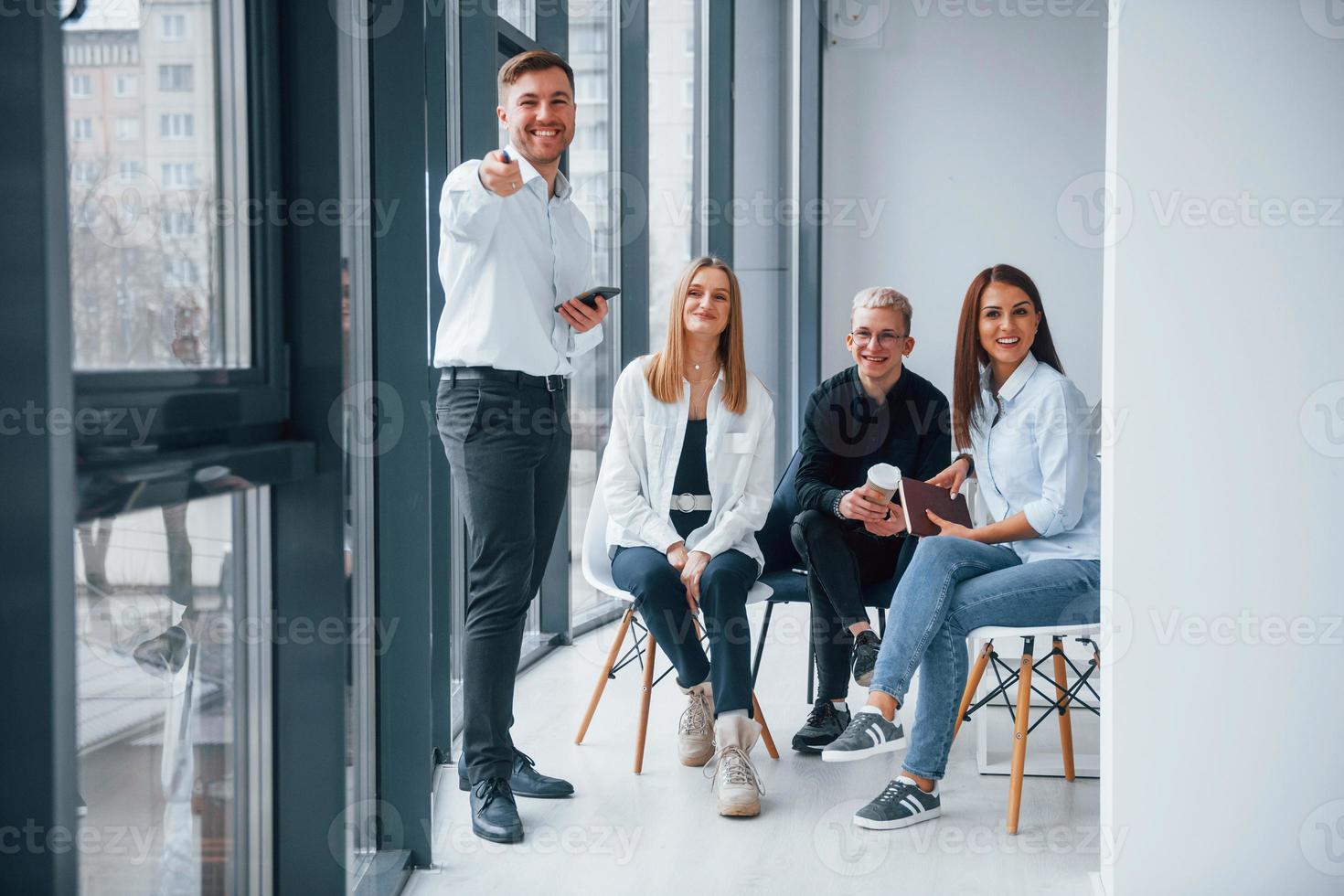 Group of young positive team have work and communicating together indoors in office near windows photo