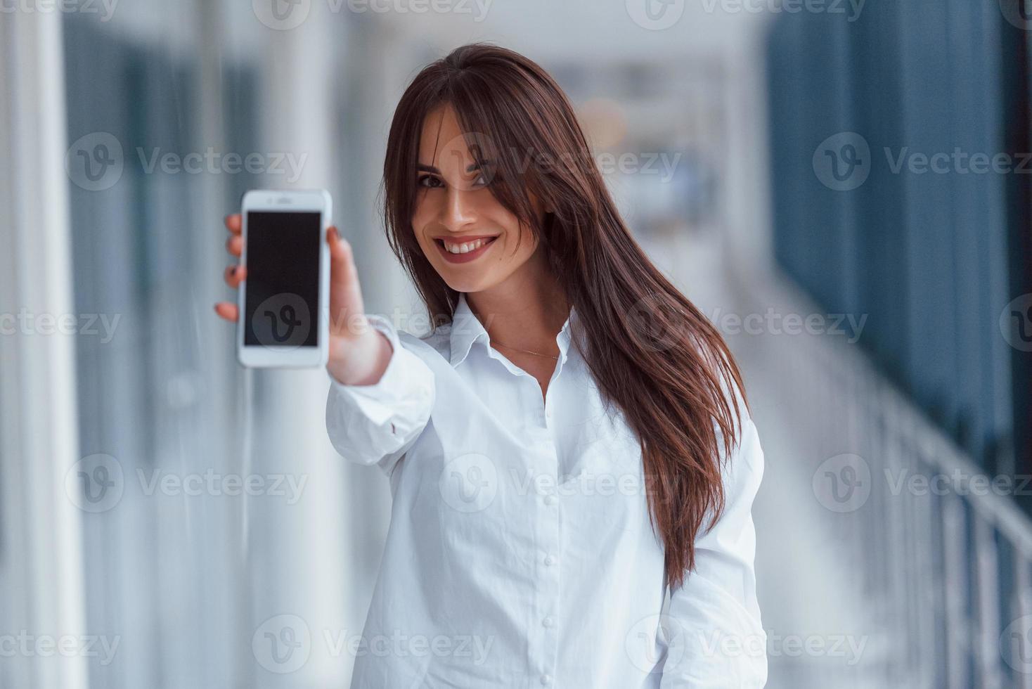 Brunette in white shirt indoors in modern airport or hallway at daytime photo