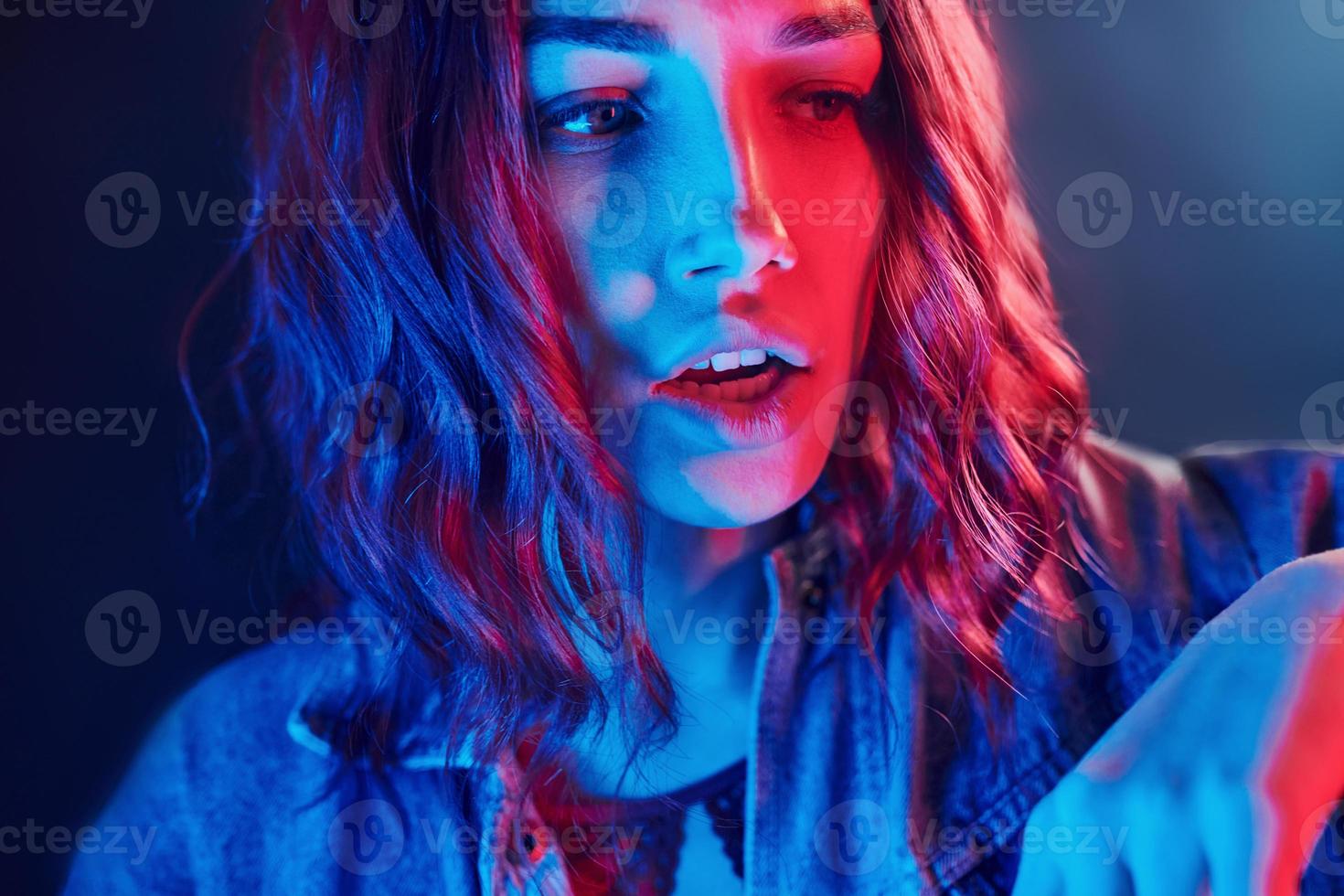 Portrait of young girl with curly hair in red and blue neon in studio photo