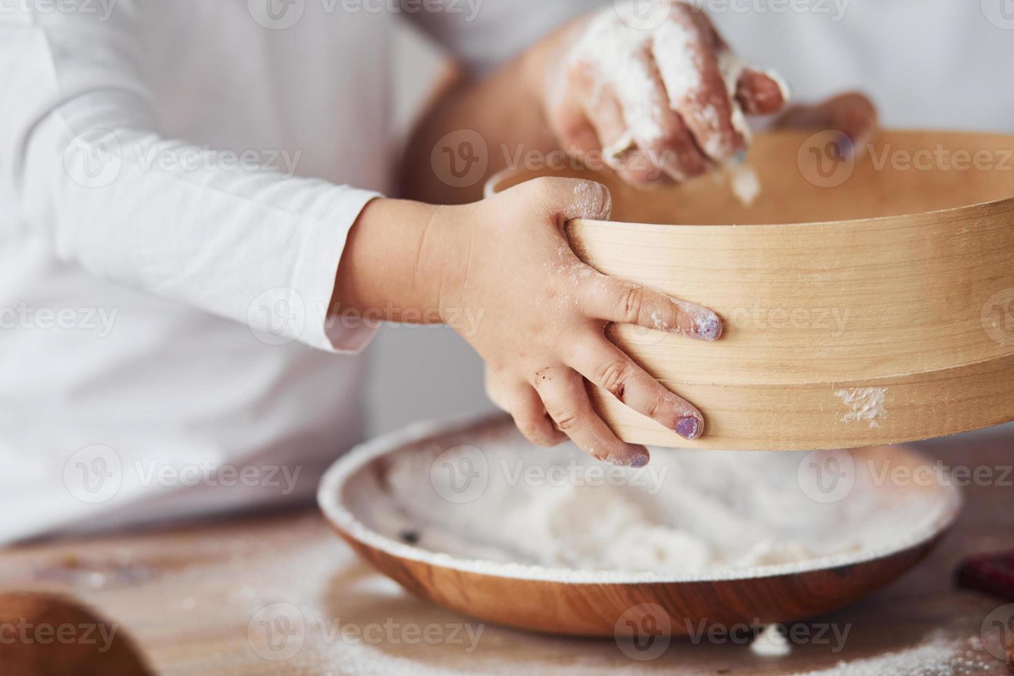 Close up view of woman with her granddaughter preparing food with flour on kitchen photo