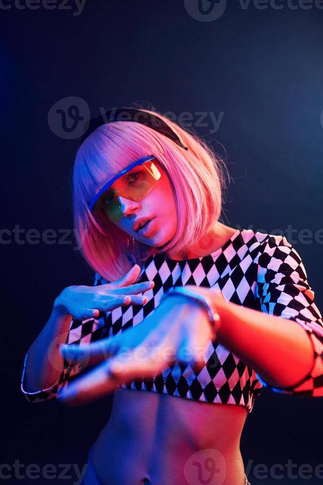 Portrait of young girl with blond hair in eyeglasses in red and blue neon in studio photo