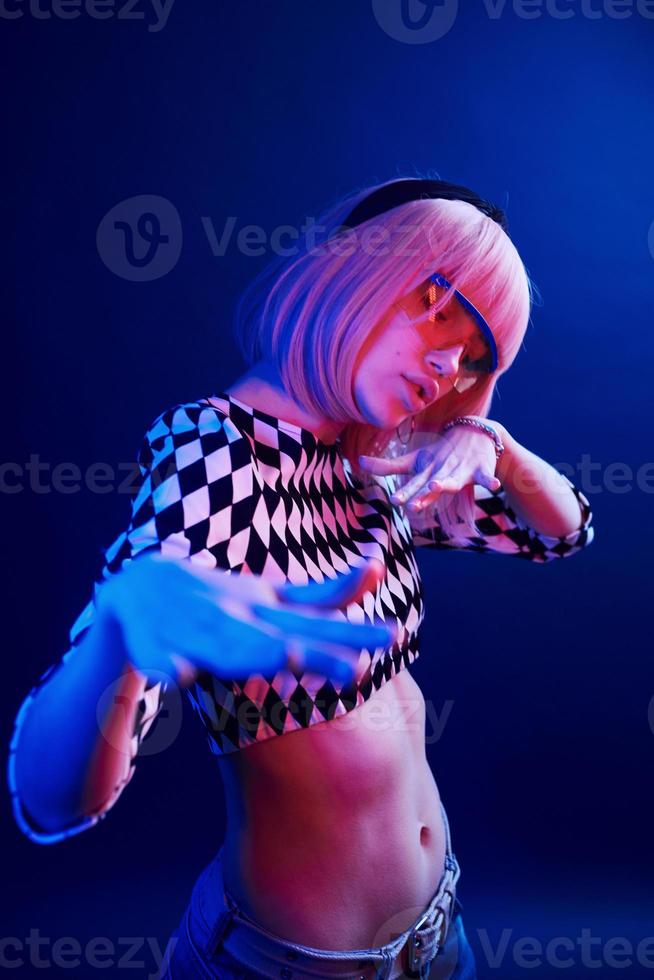 Portrait of young girl with blond hair in eyeglasses in red and blue neon in studio photo