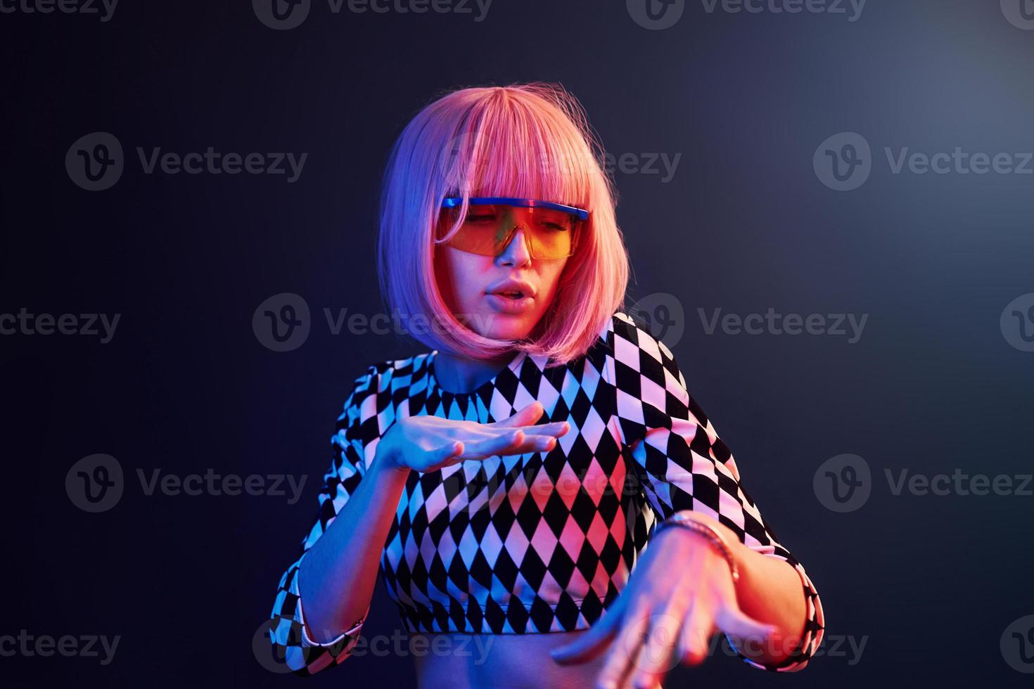 Portrait of young girl with blond hair in eyeglasses in red and blue neon in studio photo