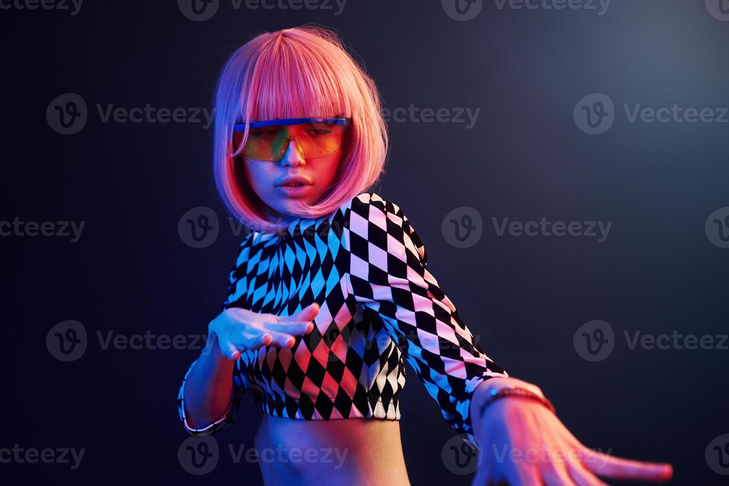 Portrait of young girl with blond hair in eyeglasses in red and blue neon in studio photo