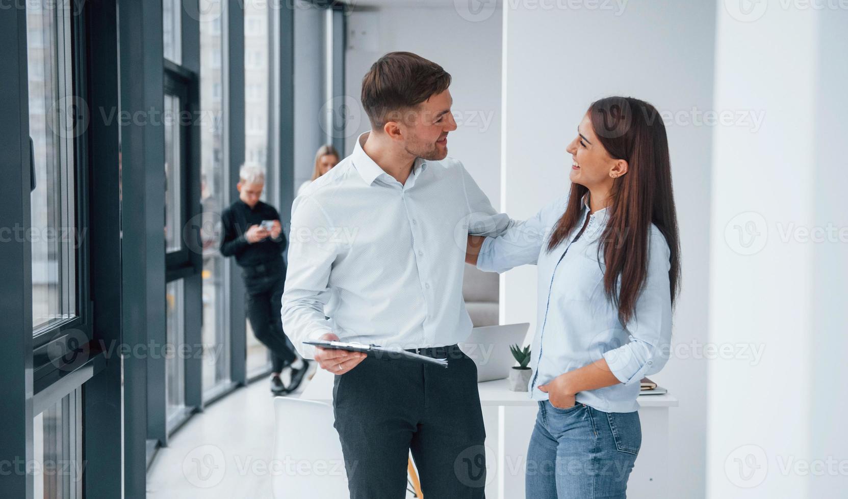 Woman and man talking about documents in front of young successful team that working and communicating together indoors in office photo