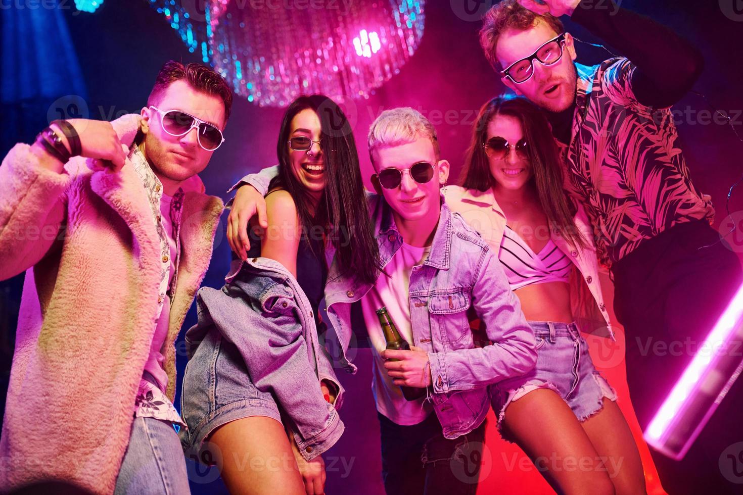 Posing for the camera. Young people is having fun in night club with colorful laser lights photo