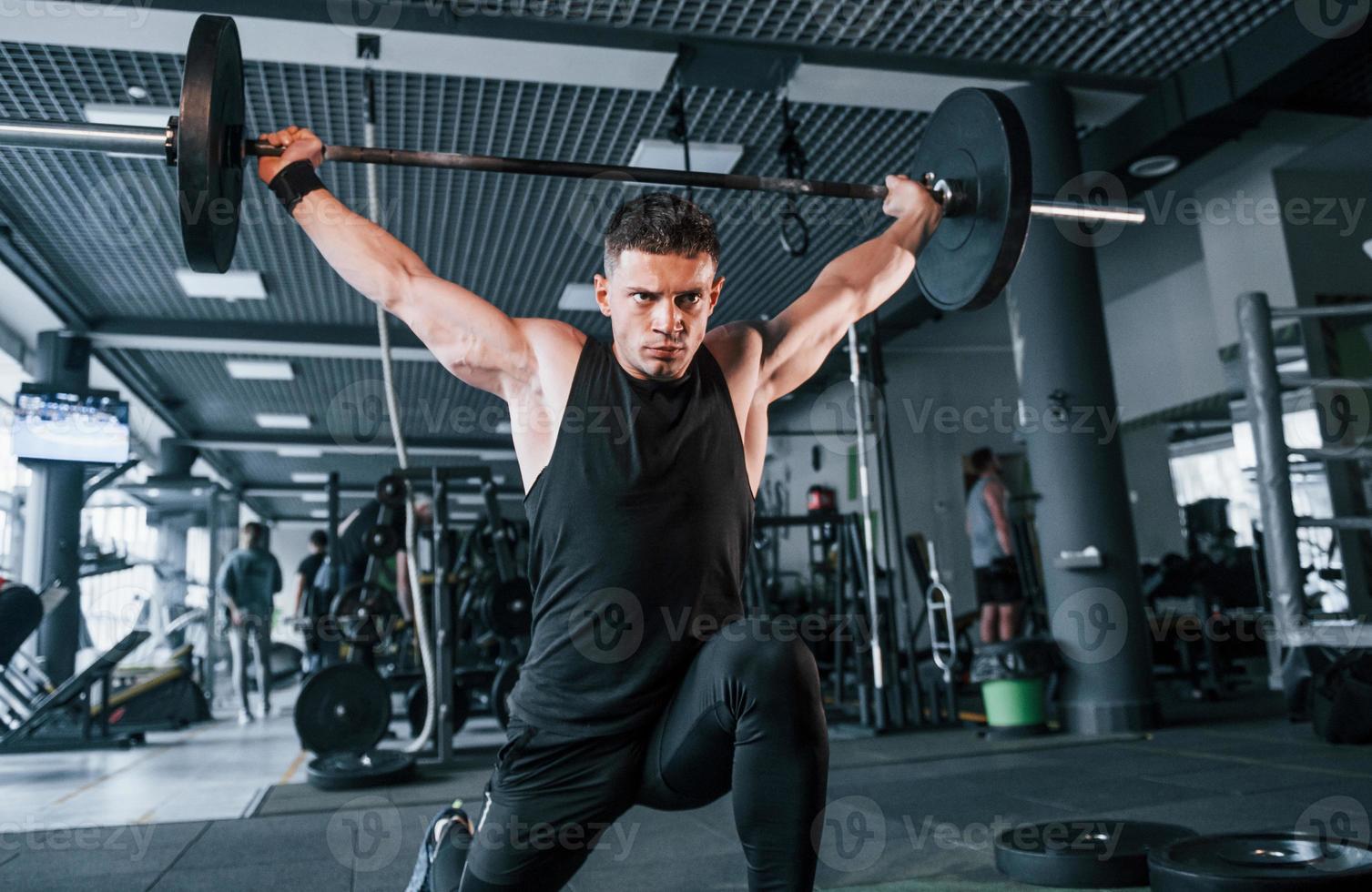 joven fuerte con ropa deportiva haciendo ejercicios con pesos pesados en el gimnasio foto