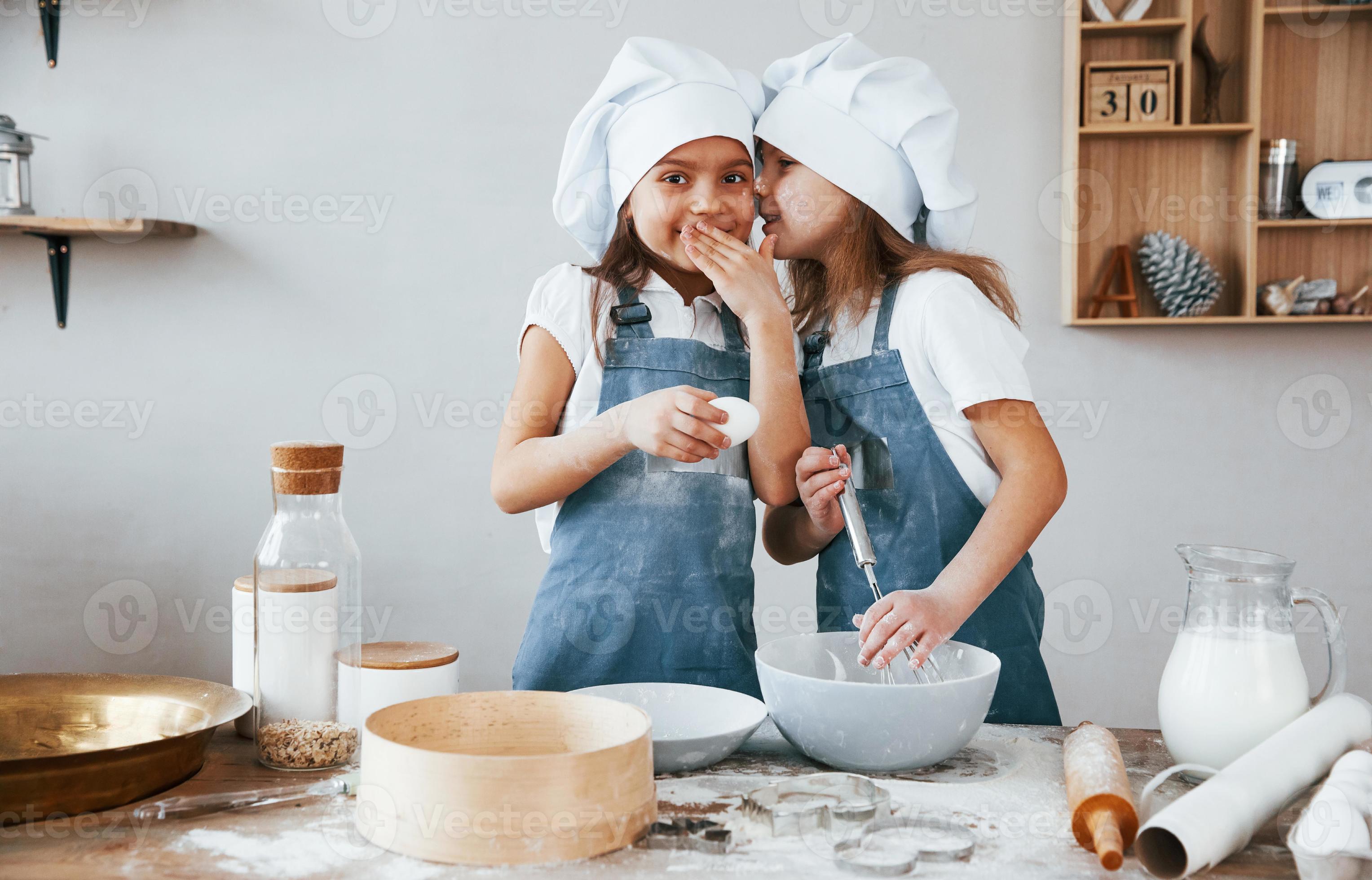 https://static.vecteezy.com/system/resources/previews/015/254/804/large_2x/two-little-girls-in-blue-chef-uniform-talking-secrets-to-each-other-when-preparing-food-on-the-kitchen-photo.jpg