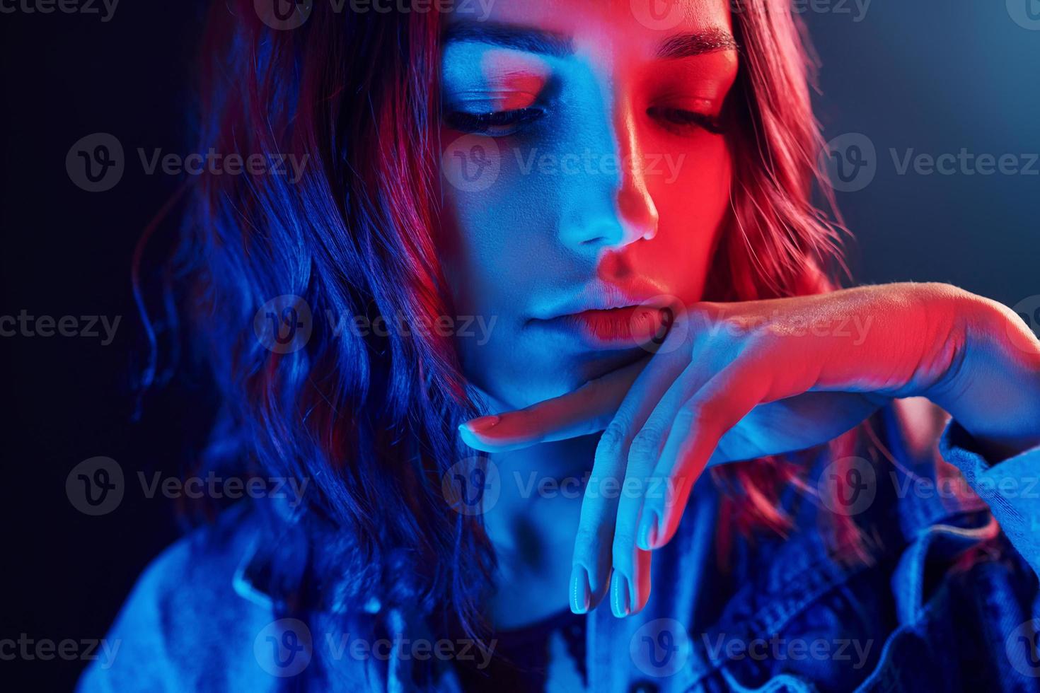 Portrait of young girl with curly hair in red and blue neon in studio photo