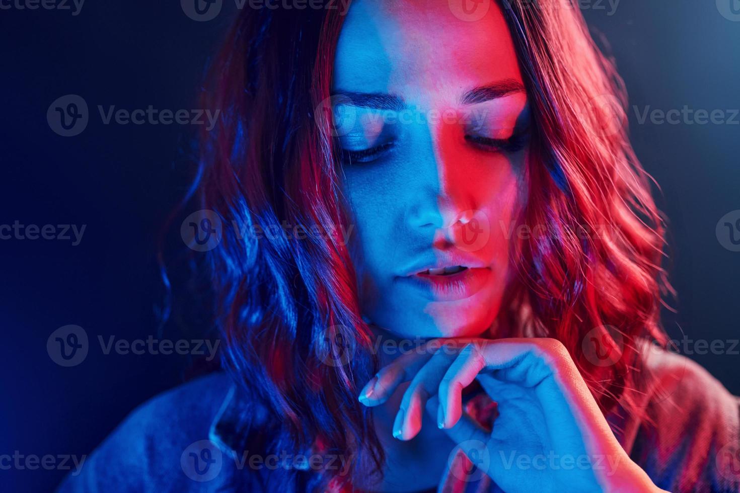 Portrait of young girl with curly hair in red and blue neon in studio photo