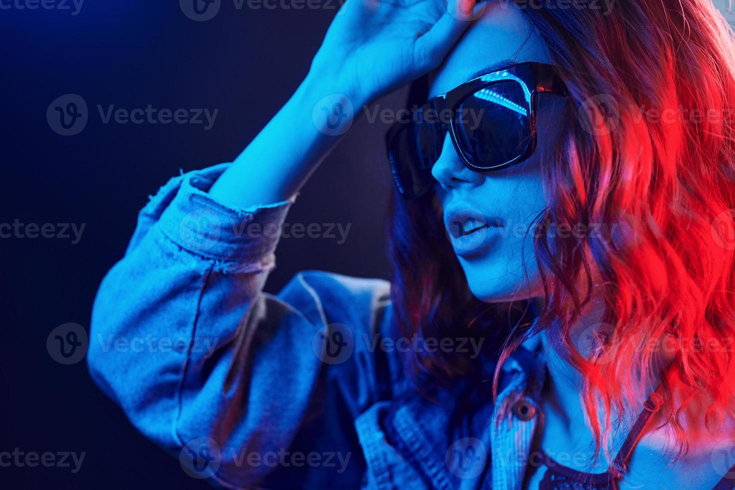 retrato de una joven con gafas de sol en neón rojo y azul en el estudio foto