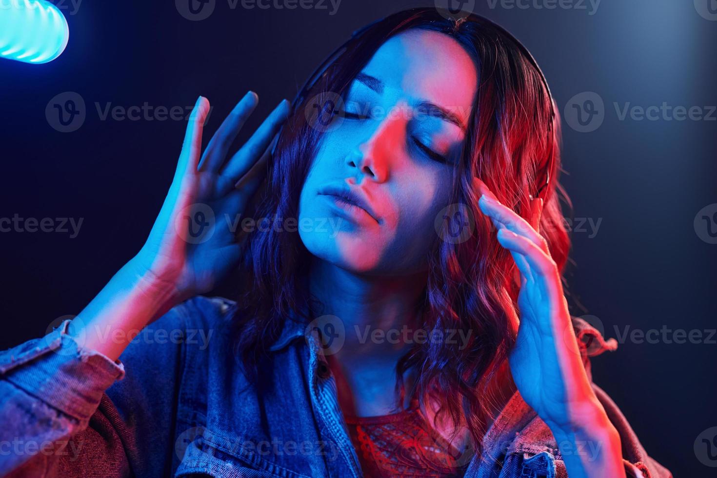 Portrait of young girl that listening to music in headphones in red and blue neon in studio photo