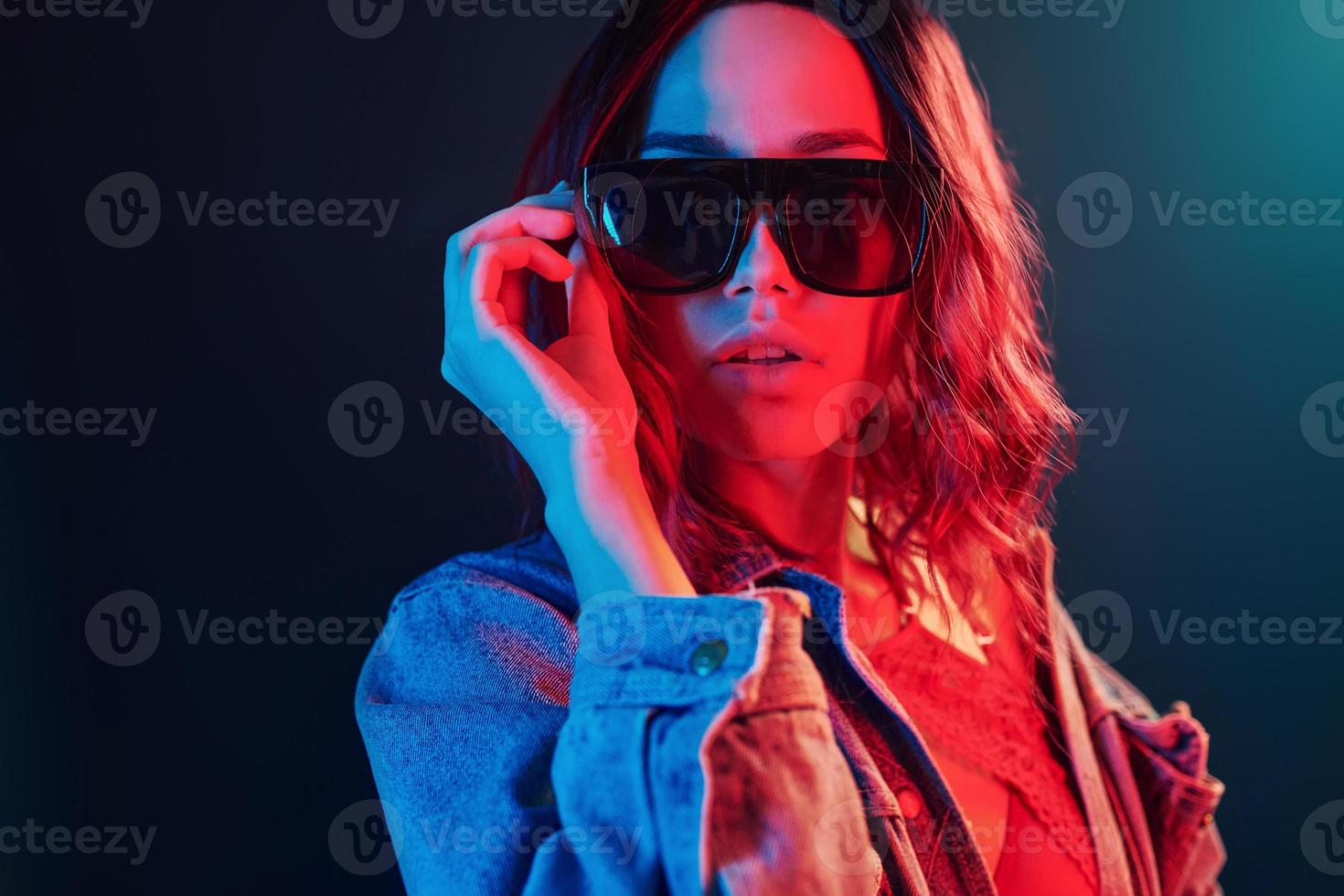 retrato de una joven con gafas de sol en neón rojo y azul en el estudio foto