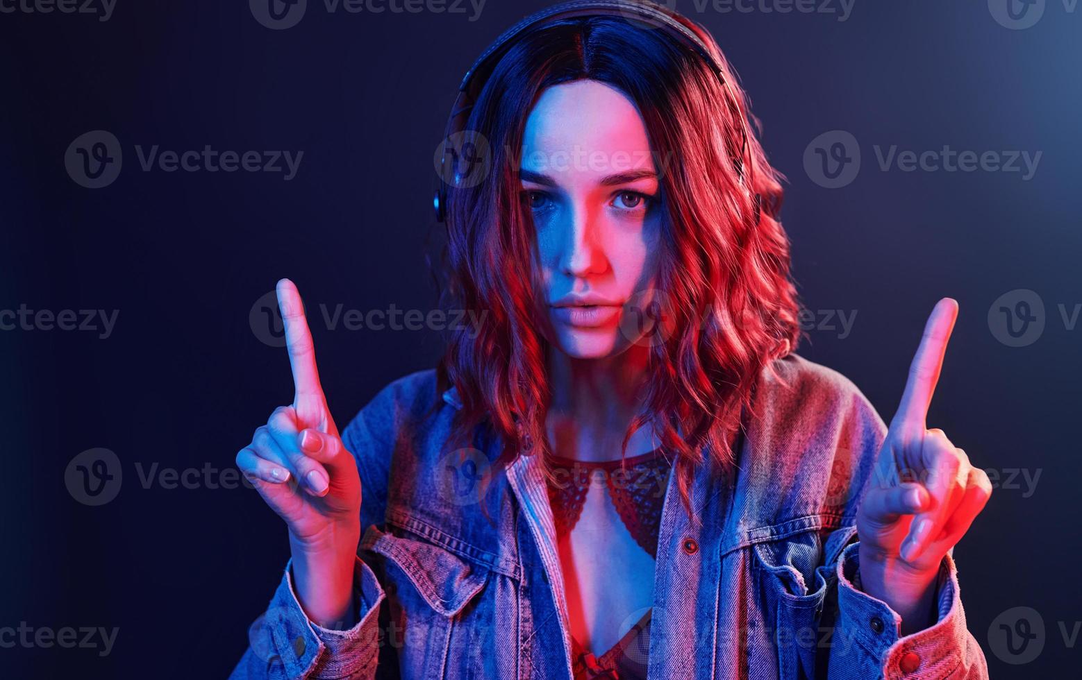 Portrait of young girl that listening to music in headphones in red and blue neon in studio photo