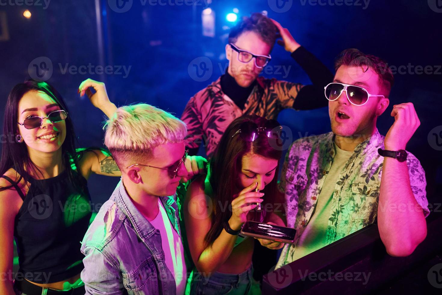 Young people sniffing drug in nightclub with colorful laser lights photo