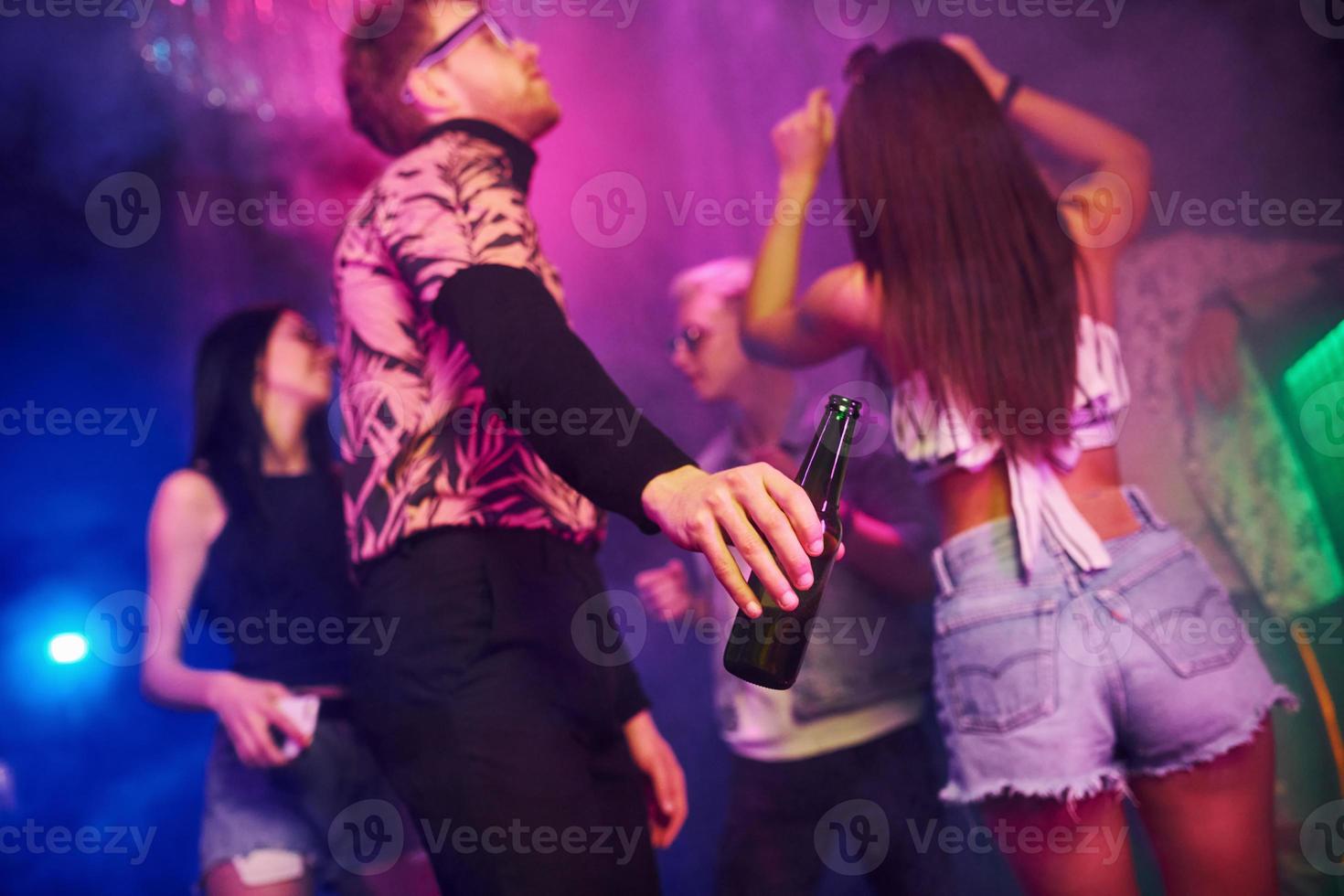 fiesta con alcohol. los jóvenes se divierten en el club nocturno con luces láser de colores foto