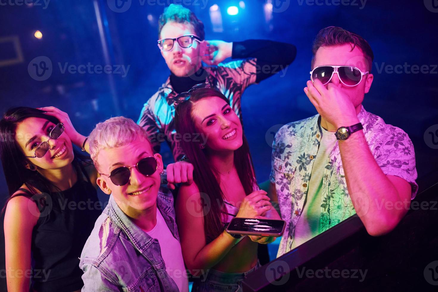 Young people sniffing drug in nightclub with colorful laser lights photo