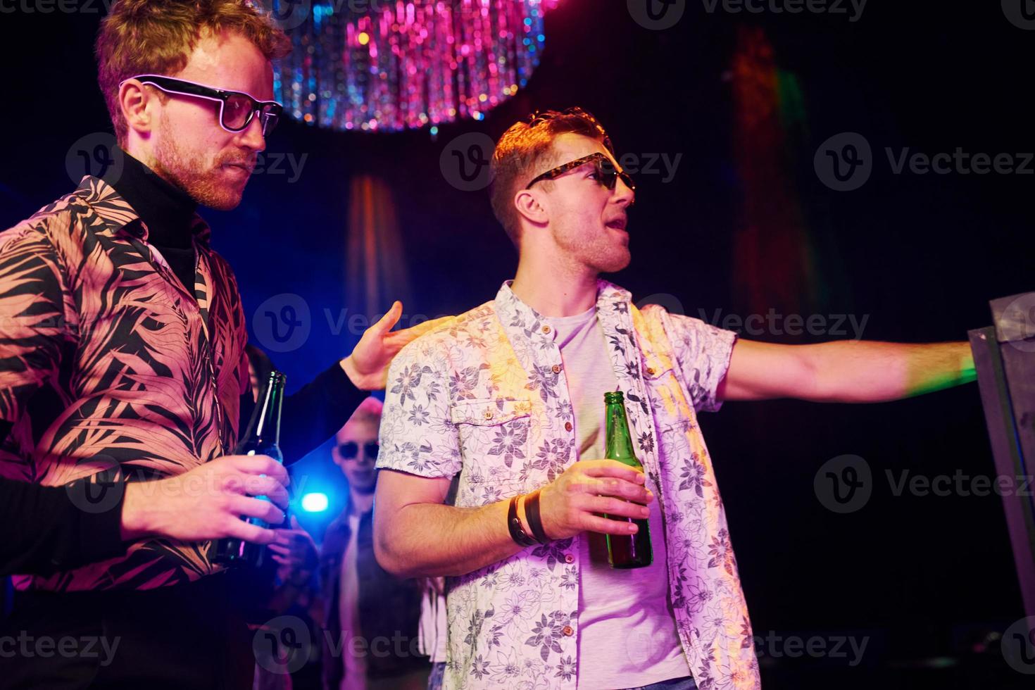 Young people is having fun in night club with colorful laser lights photo