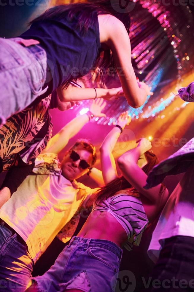 View from below of young people that having fun in night club with colorful laser lights photo