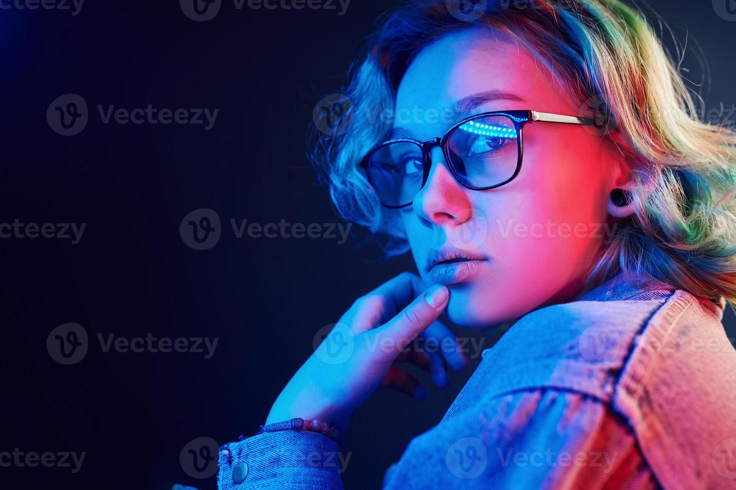 Portrait of young alternative girl in glasses with green hair in red and blue neon light in studio photo