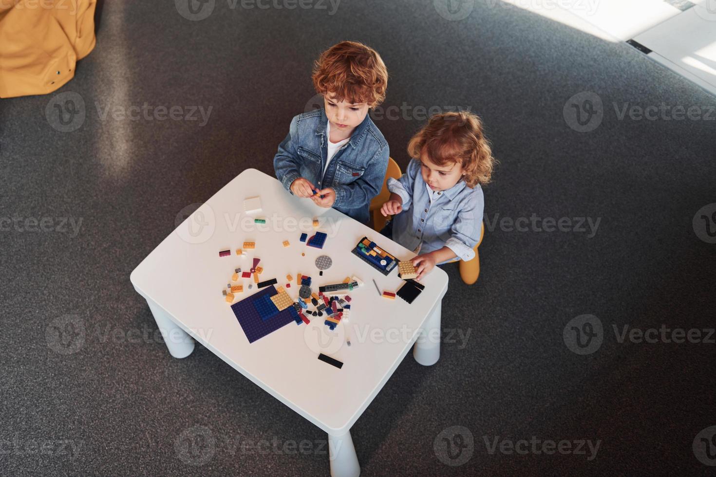 Little friends have fun with construction toys in playroom. Kindergarten educational games photo