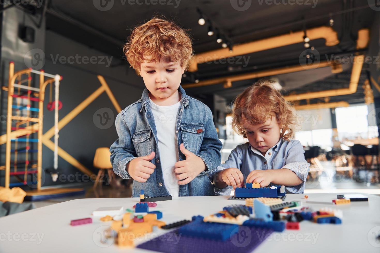 Little friends have fun with construction toys in playroom. Kindergarten educational games photo