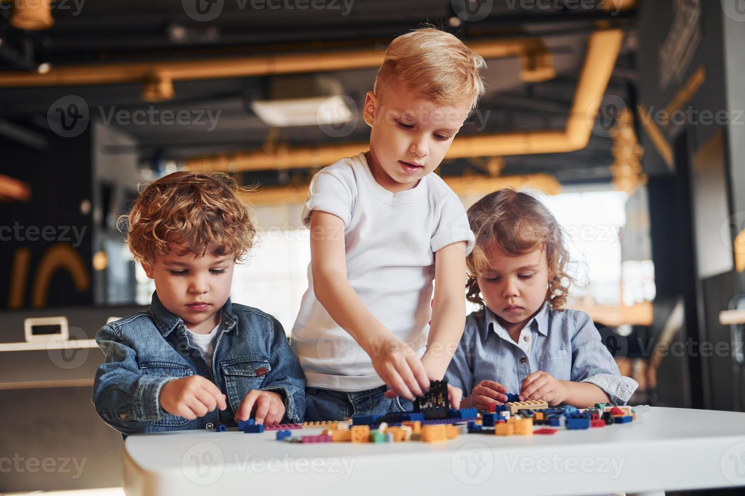 Little friends have fun with construction toys in playroom. Kindergarten educational games photo