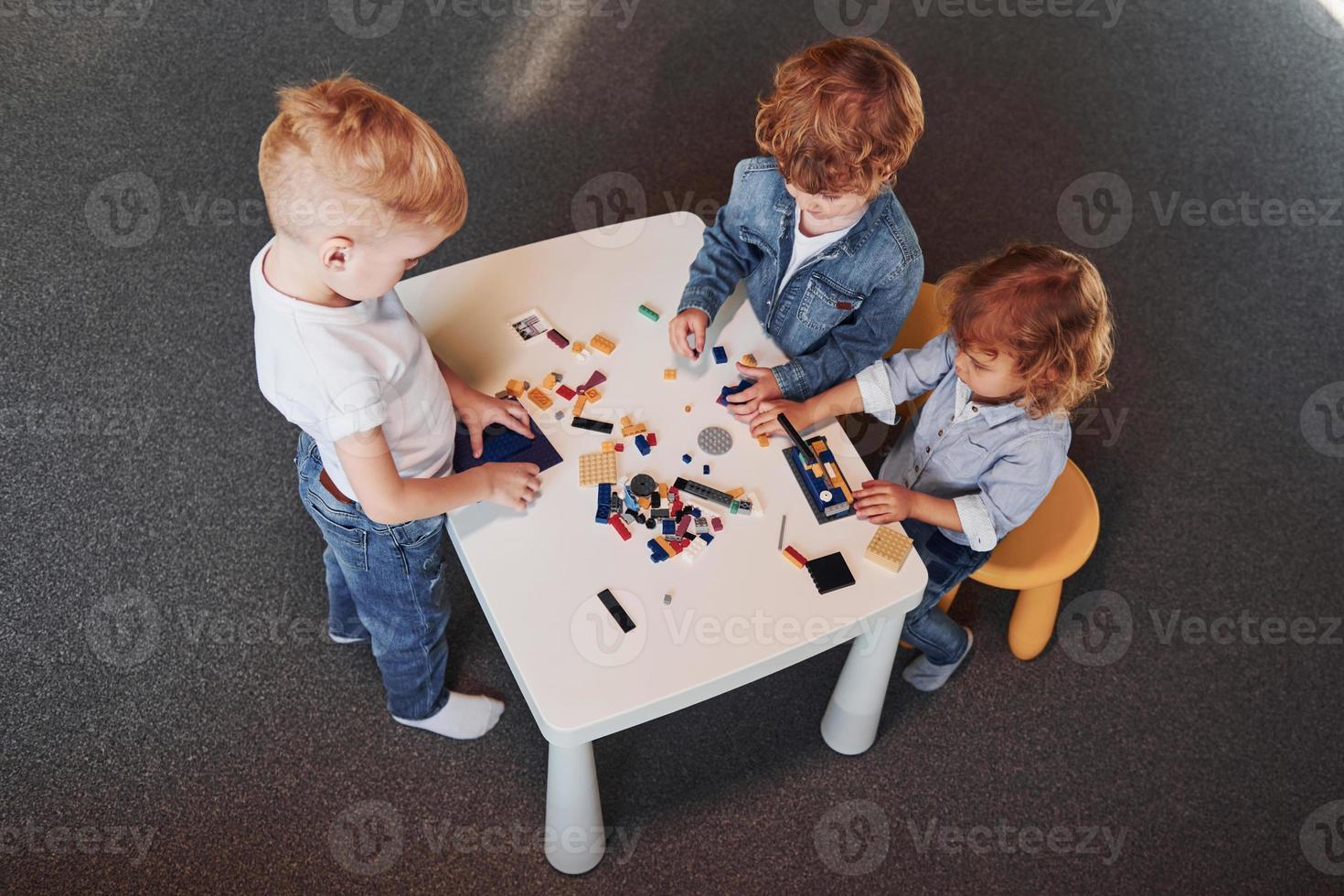 Little friends have fun with construction toys in playroom. Kindergarten educational games photo