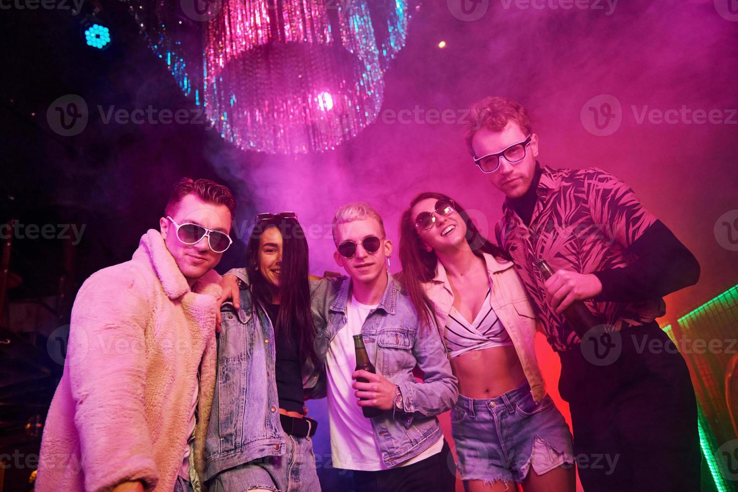 Posing for the camera. Young people is having fun in night club with colorful laser lights photo