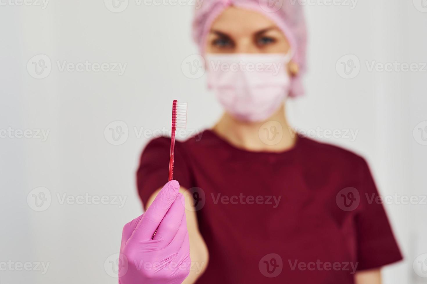 Young female dentist in uniform standing in stomatology office and holding brush photo