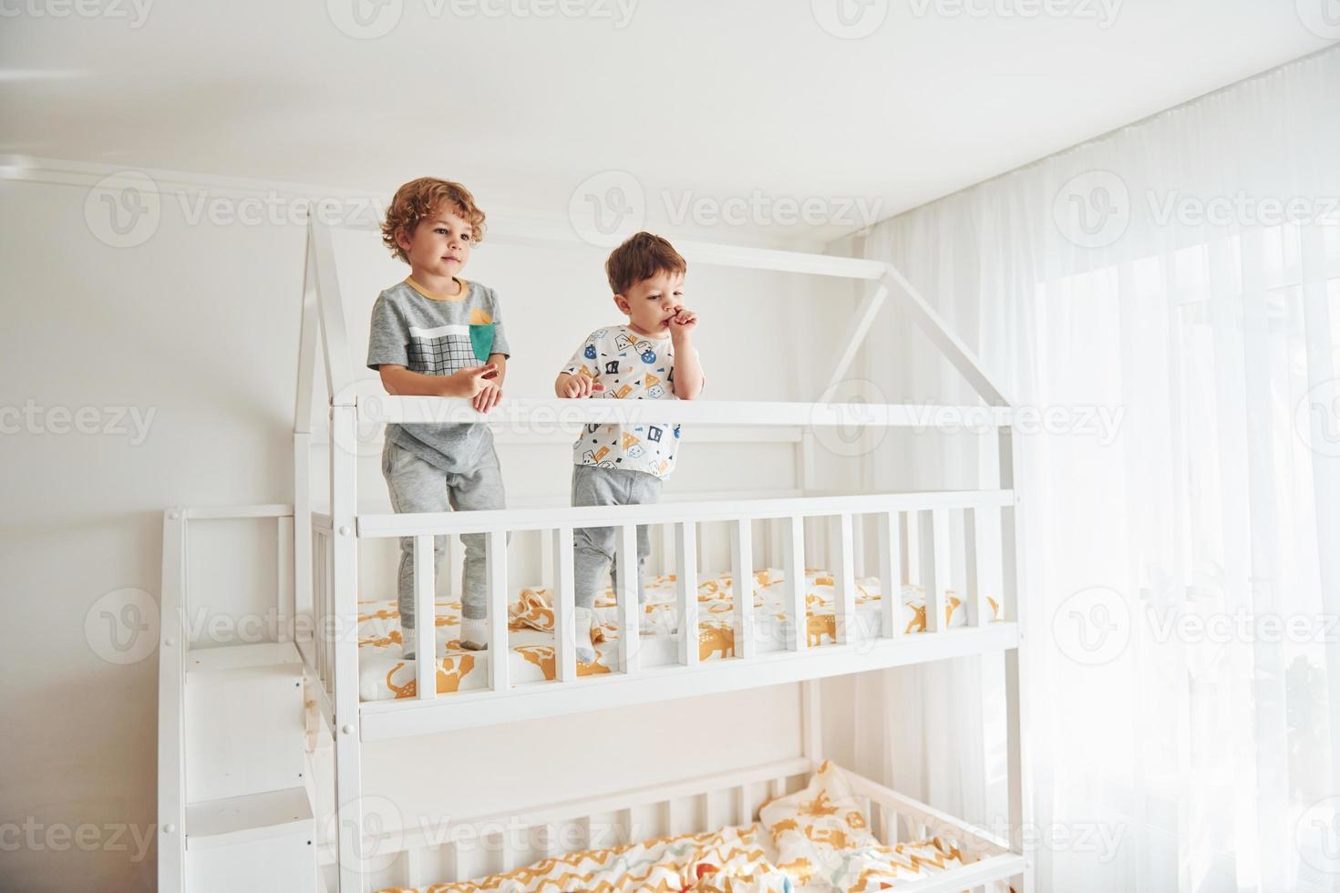 dos niños pequeños descansan y se divierten juntos en el interior del dormitorio foto