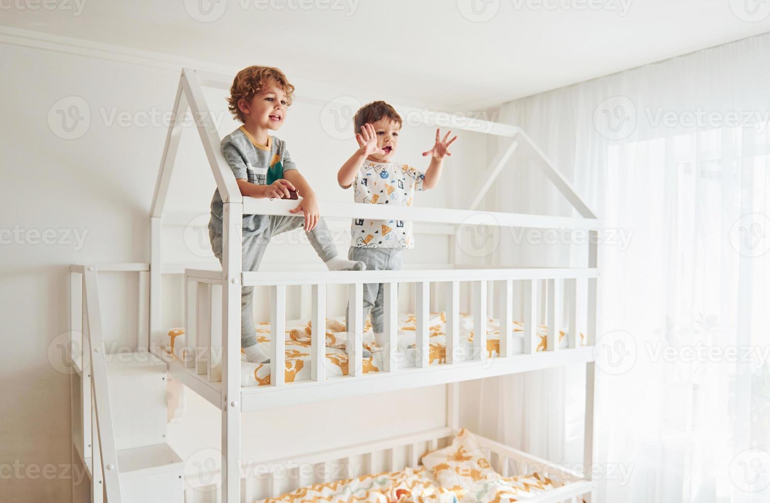 Two little boys resting and have fun indoors in the bedroom together photo